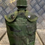 Green camouflage canteen with a metal cap on a wooden surface with a metallic background