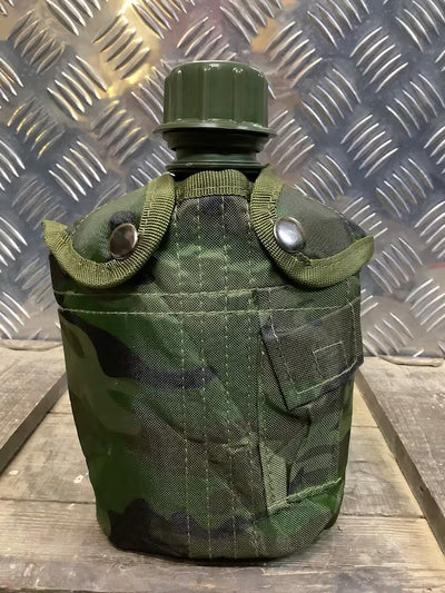 Green camouflage canteen with a metal cap on a wooden surface with a metallic background