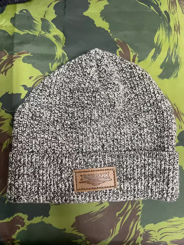 Knitted beanie with a leather patch on a green camouflage background