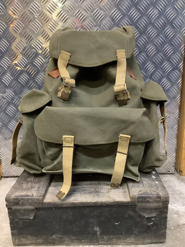 Green backpack with beige straps on a metal surface