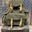 Green backpack with beige straps on a metal surface