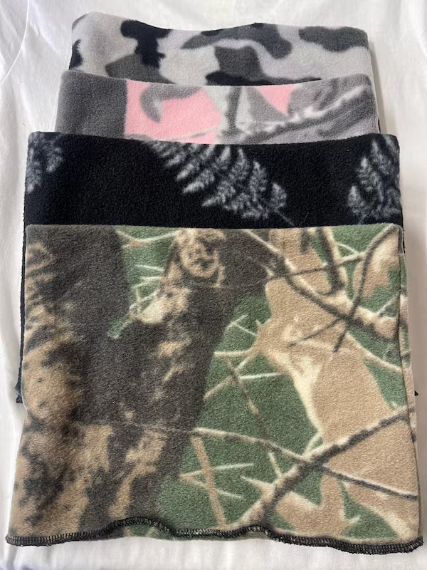 Four camouflage-patterned blankets stacked on a white background