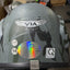 Gray helmet with 'VIA Helmet' branding and safety certification logos on a blurred indoor background.