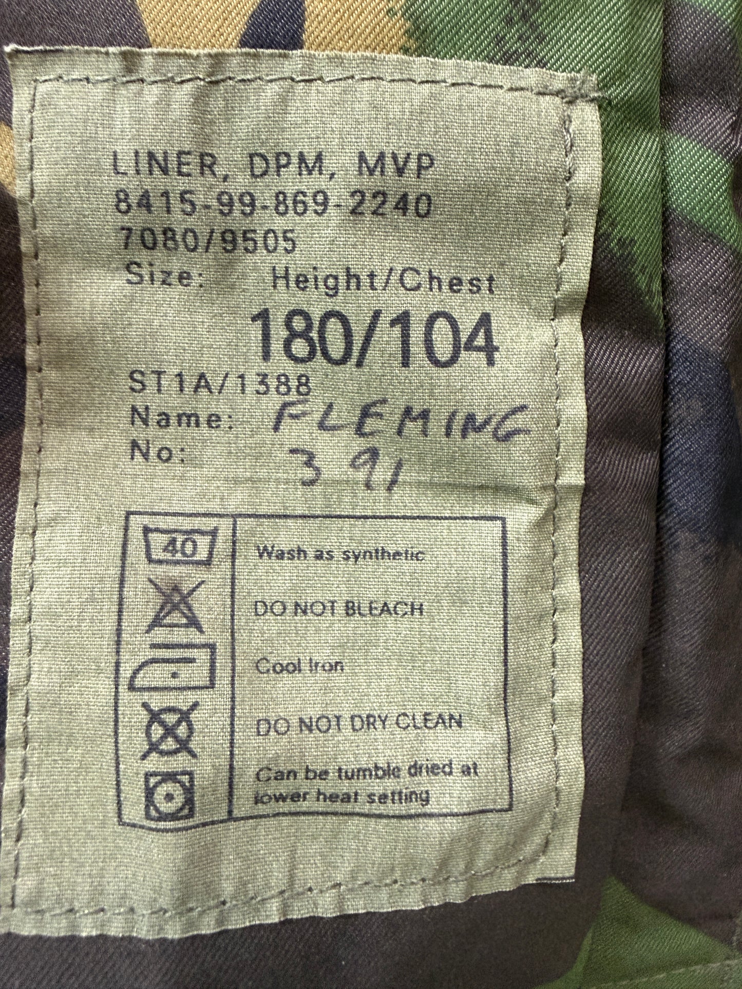 Fabric label with size and care instructions on a camouflage background