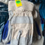 Pair of beige and gray work gloves with a yellow tag on a surface.