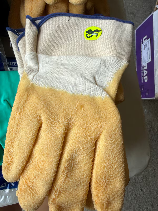 Beige glove with white cuff and blue trim on a gray surface