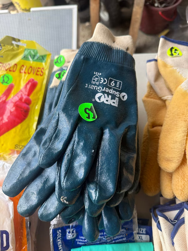 Pair of blue gloves with a brand logo on a shelf with other items.