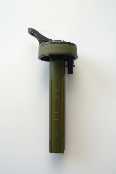 An olive green tactical water filter straw with a black flip-top lid and measurement markings on the handle, shown against a plain white background.