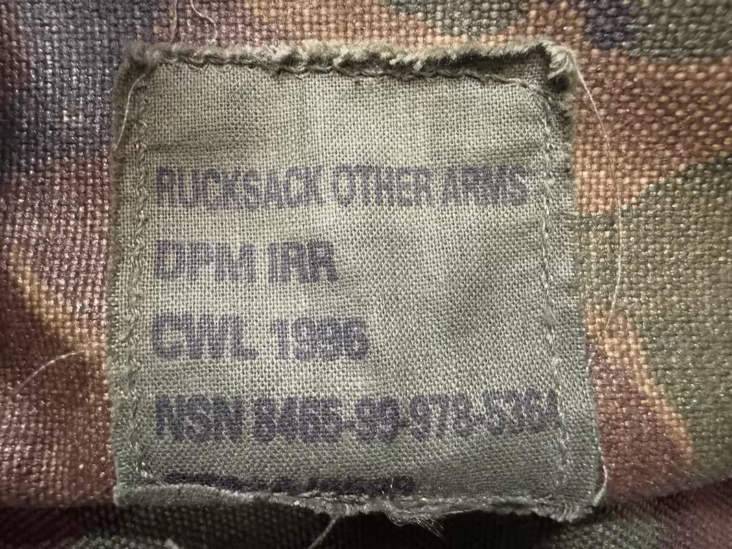 Fabric tag on a camouflage-patterned background with text and numbers.