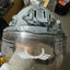 Helmet with clear visor held by a gloved hand, with a blurred background