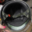 Close-up of a helmet interior with a hand holding it, on a cluttered background.