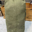 Green canvas bag on a concrete floor with wooden shelves in the background