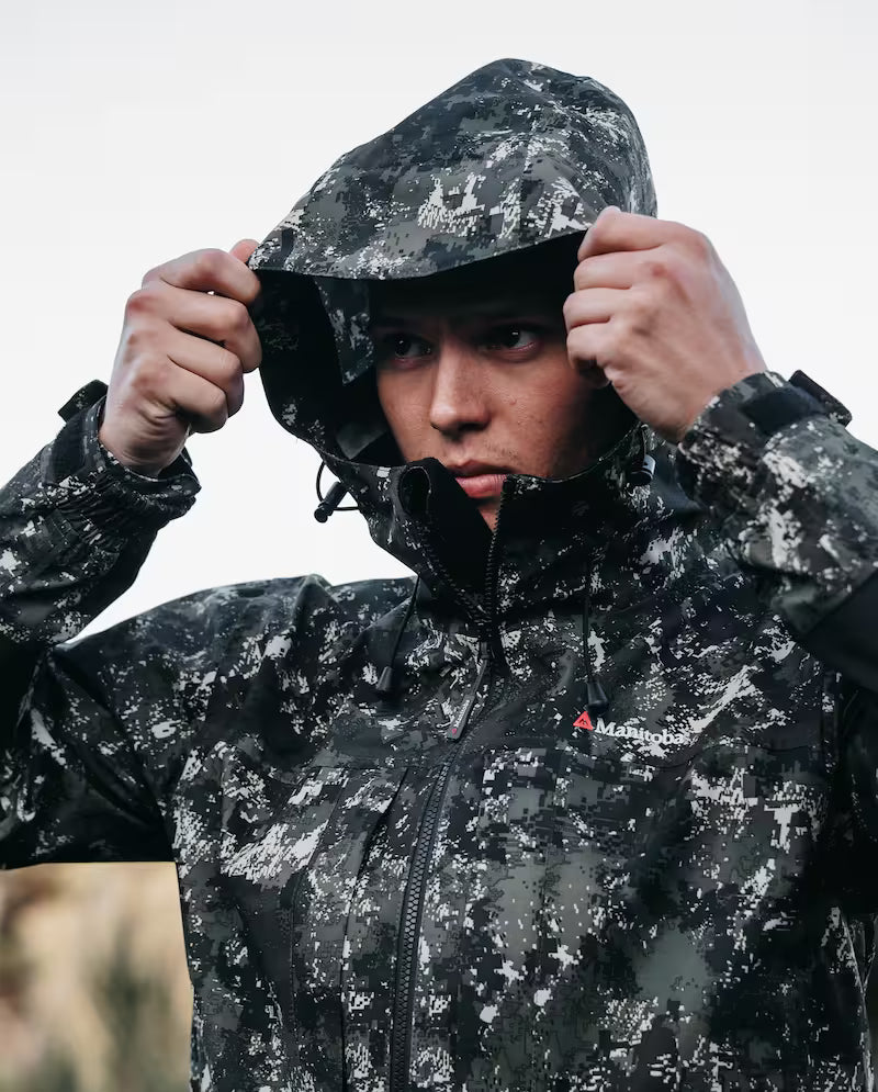 Person wearing a black and gray camouflage raincoat with a brand logo.