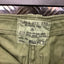 Close-up of a label on a green garment with 'Yakka Pty. Ltd.' branding.
