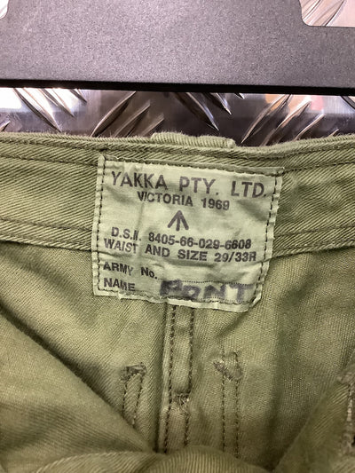 Close-up of a label on a green garment with 'Yakka Pty. Ltd.' branding.