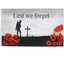 Memorial flag with silhouette of a soldier, cross, and red poppies with 'Lest we forget...' text.