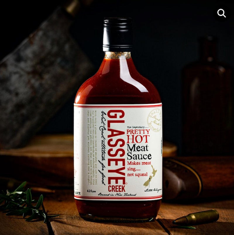 Bottle of Glasseye Creek meat sauce on a wooden surface with a dark background