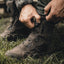 Person tying a boot in a grassy area