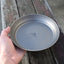 Hand holding a metallic plate with a brand logo on a wooden surface