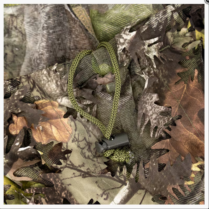 Close-up of a camouflage-patterned fabric with a green rope and gray object.