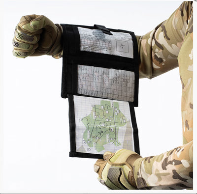 Person wearing camouflage gloves holding a tactical map in a pouch.