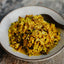 Stir-fried dish with rice and meat in a bowl on a textured surface