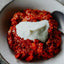 Red dish with a white dollop of cream on a white plate