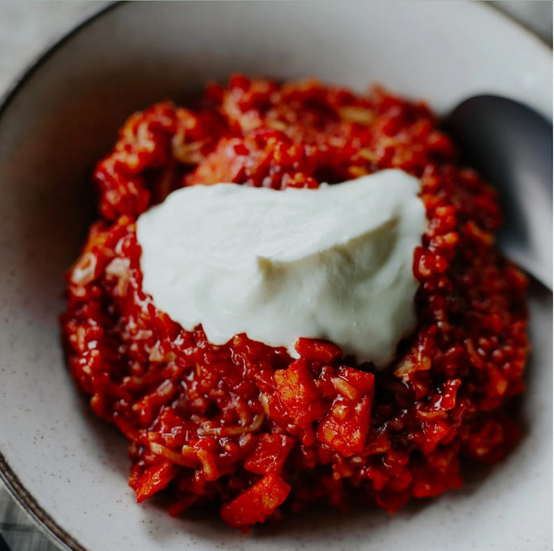 Red dish with a white dollop of cream on a white plate