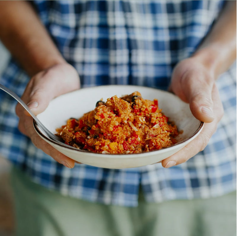 Person holding a bowl of food with a checkered shirt