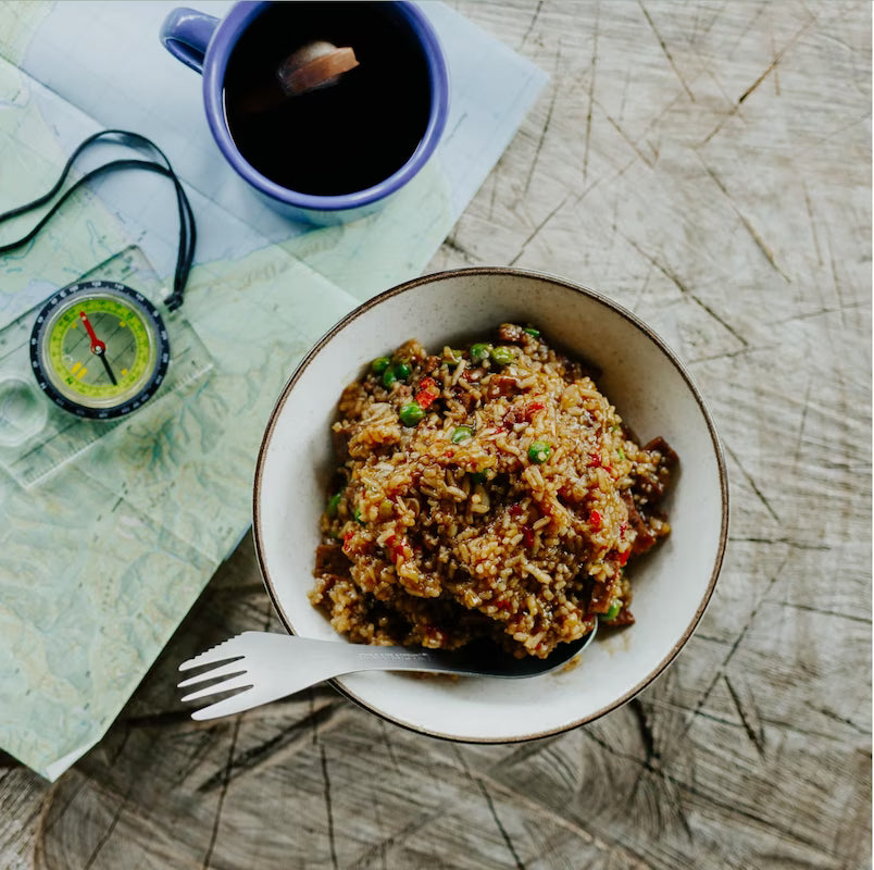 Bowl of food with a cup of tea and map on a wooden surface