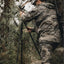 Hunter in camouflage gear using a bow in a forest setting