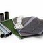 Collection of camping and outdoor gear including a green notebook, gray fabric pouch, and metal tubes on a white background.