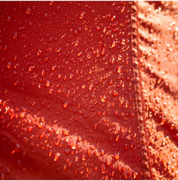 Close-up of a red surface with water droplets and a textured brown background.