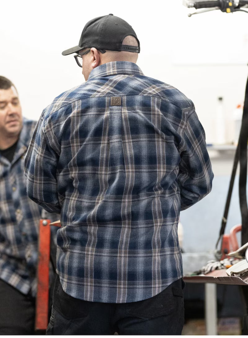 Man wearing a blue plaid shirt and black cap in an indoor setting