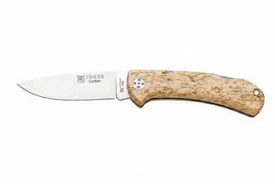 A pocket knife with a silver stainless steel blade and a textured, light tan wood handle, shown against a plain white background. The blade features the 'Cocker' brand name and logo.