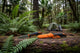 Two knives on a log with a forest background