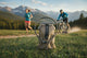 Person running and mountain biking with a hydration bladder in the foreground, set against a scenic mountain backdrop.