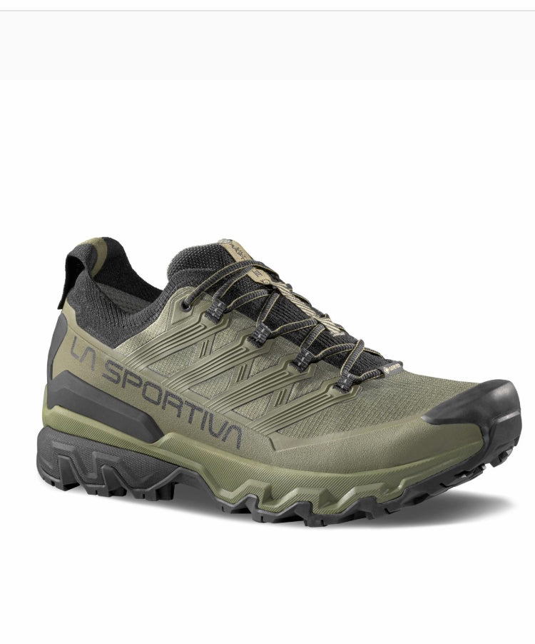 Green hiking shoe with black sole on a white background