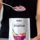 Spoonful of mixed berry powder above a radix breakfast mix package.