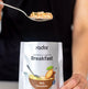 Person holding a spoonful of food above a radix breakfast package.