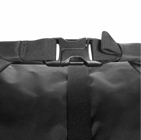 Close-up of a black waterproof bag with a roll-top closure, featuring a black plastic quick-release buckle and adjustable webbing strap on a white background.