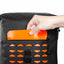 A close-up of a black backpack with an orange waterproof flap pocket being opened by a hand, showing the interior drainage holes below.