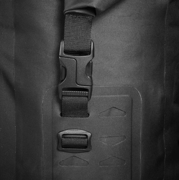 Close-up of a black backpack with straps and a brand logo on a dark background