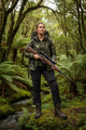 Person in camouflage clothing holding a rifle in a forest setting