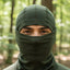 Person wearing a green balaclava in a forest setting