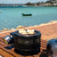 Portable grill with food on a wooden deck by a waterfront