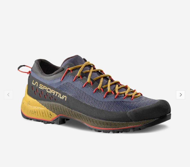 A single La Sportiva trail running shoe shown from a three-quarters angle against a light gray background. The shoe features a dark gray and navy blue mesh upper, mustard yellow laces, a yellow midsole, and red accents on the outsole and heel pull tab.