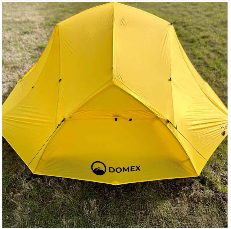 Yellow tent with DOMEX logo on a grassy background