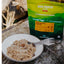 Back Country Cuisine cinnamon rice porridge package with a bowl of porridge and a fork on a stone surface.