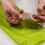 Person peeling a clear plastic sheet over a green surface